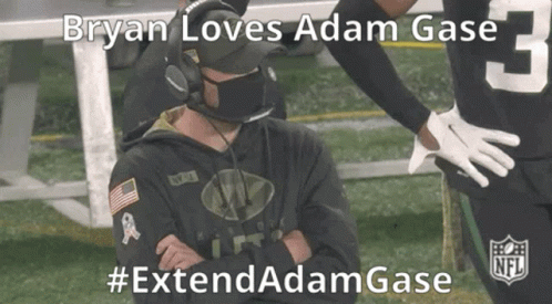 A Man Wearing A Mask And Headphones Is Sitting On The Sidelines Of A Football Field . GIF