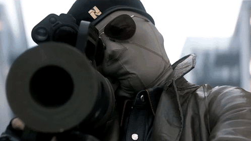 a man wearing a mask and sunglasses is aiming a gun