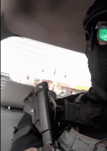 A Man Wearing A Mask And Sunglasses Is Holding A Gun In His Hand GIF