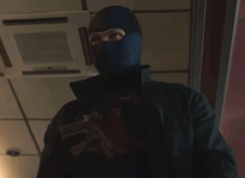 A Man Wearing A Mask Holds A Gun GIF