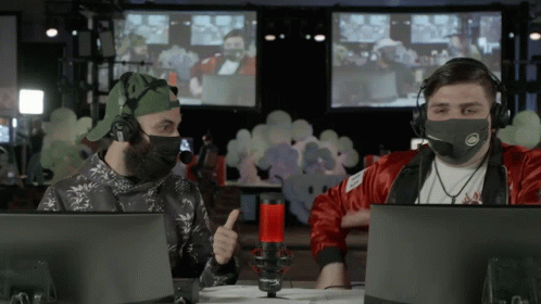 A Man Wearing A Mask Is Giving A Thumbs Up While Sitting In Front Of A Microphone GIF