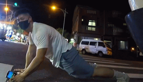 A Man Wearing A Mask Is Laying On The Ground Using His Phone GIF