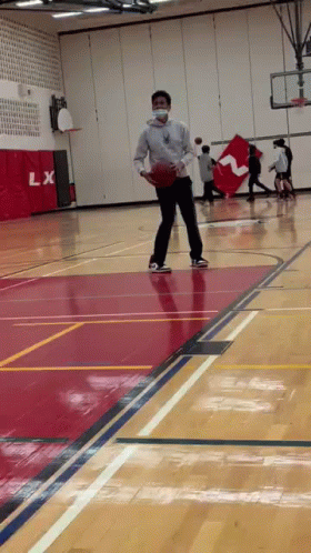 A Man Wearing A Mask Is Playing Basketball On A Court . GIF