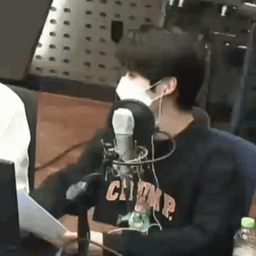 A Man Wearing A Mask Is Sitting In Front Of A Microphone In A Radio Station . GIF