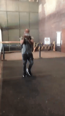 A Man Wearing A Mask Is Standing In A Room With A Fence In The Background GIF