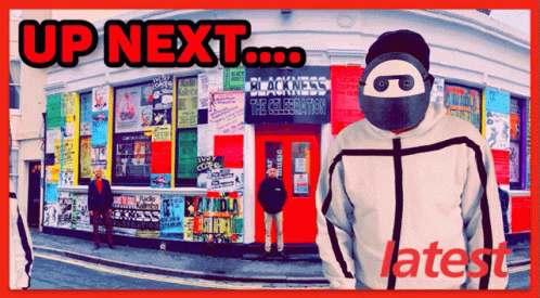 A Man Wearing A Mask Is Standing In Front Of A Building That Says Up Next GIF