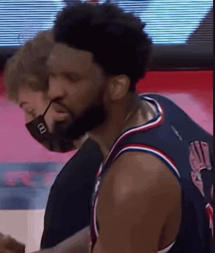 A Man Wearing A Mask Is Standing Next To A Basketball Player Wearing A Jersey . GIF