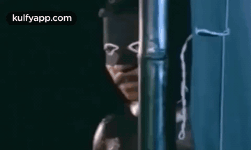 A Man Wearing A Mask Is Standing Next To A Pipe . GIF