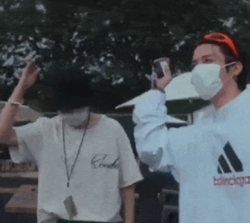 A Man Wearing A Mask Is Taking A Picture Of Another Man . GIF