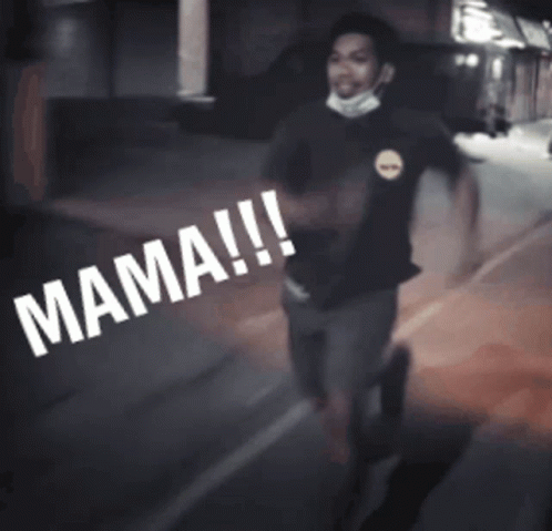 A Man Wearing A Mask Is Walking Down A Street With The Word Mama Written On The Ground GIF