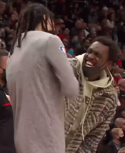 A Man Wearing A Mask Laughs With Another Man In A Crowd GIF