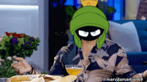 A Man Wearing A Mask Of Marvin The Martian Holds A Glass Of Orange Juice GIF