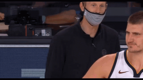 A Man Wearing A Mask Stands Next To A Man Wearing A Nike Shirt GIF