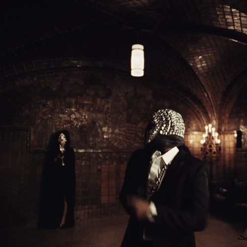 A Man Wearing A Mask With Rhinestones Is Standing In A Dark Room GIF