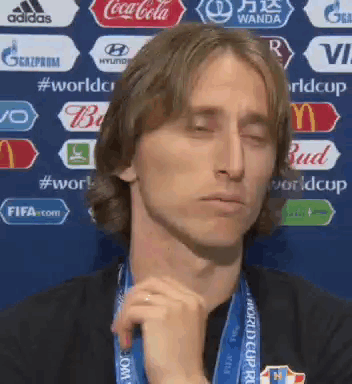 A Man Wearing A Medal Around His Neck Is Making A Funny Face With His Eyes Closed . GIF