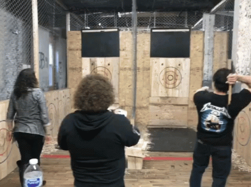 A Man Wearing A Metallica Shirt Throws An Axe GIF
