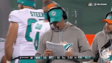 A Man Wearing A Miami Dolphins Hat Is Holding A Piece Of Paper GIF