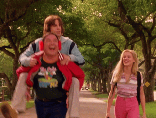 A Man Wearing A Mickey Mouse Shirt Is Carrying Another Man GIF