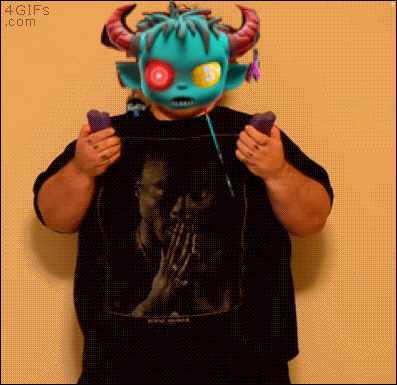 A Man Wearing A Monster Mask Is Holding A Pair Of Remote Controls GIF