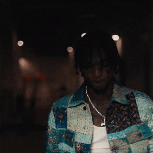 A Man Wearing A Necklace With A Cross On It Looks Down GIF