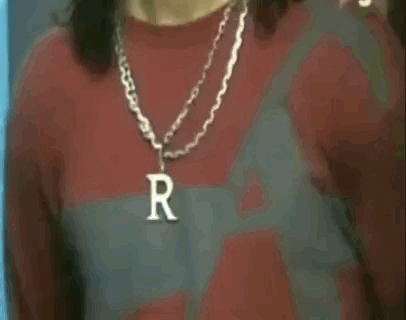 A Man Wearing A Necklace With A Letter R On It . GIF