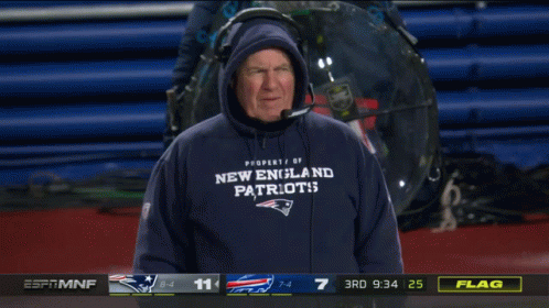 A Man Wearing A New England Patriots Sweatshirt Stands In Front Of A Scoreboard GIF
