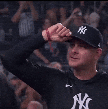 a man wearing a new york yankees hat holds up his fist