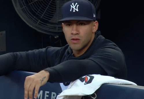 A Man Wearing A New York Yankees Hat Sits In A Dugout GIF