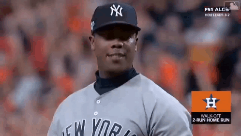 A Man Wearing A New York Yankees Jersey Stands In Front Of A Sign That Says Walk Off 2 Run Home Run GIF