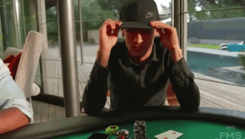 A Man Wearing A Nike Hat Is Sitting At A Poker Table GIF