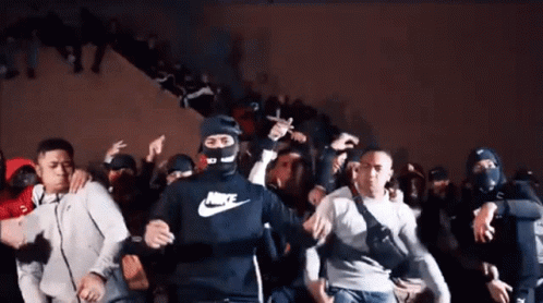 A Man Wearing A Nike Shirt Is Dancing In A Crowd Of People GIF