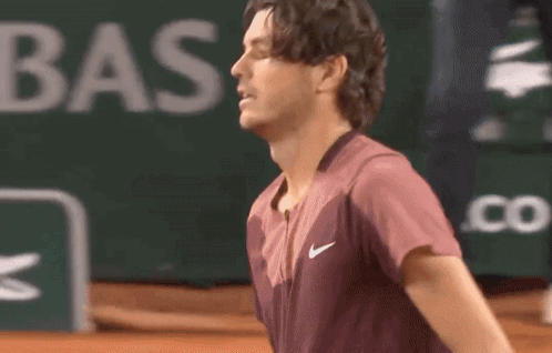 A Man Wearing A Nike Shirt Is Standing On A Tennis Court .. GIF