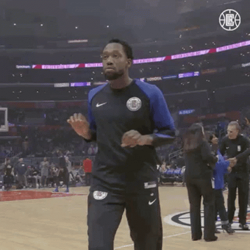 A Man Wearing A Nike Shirt Is Walking On A Basketball Court .. GIF