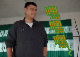 A Man Wearing A Nike Sweatshirt Is Standing In Front Of A Green And White Curtain GIF