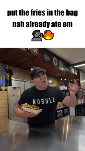 A Man Wearing A Nobull Shirt Is Holding A Tray Of French Fries GIF