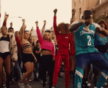 A Man Wearing A Number 2 Jersey Is Dancing With A Group Of People GIF
