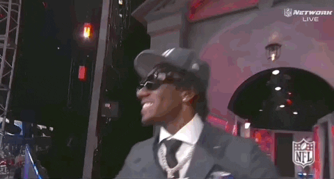 A Man Wearing A Ny Hat And Sunglasses Stands In Front Of A Screen GIF
