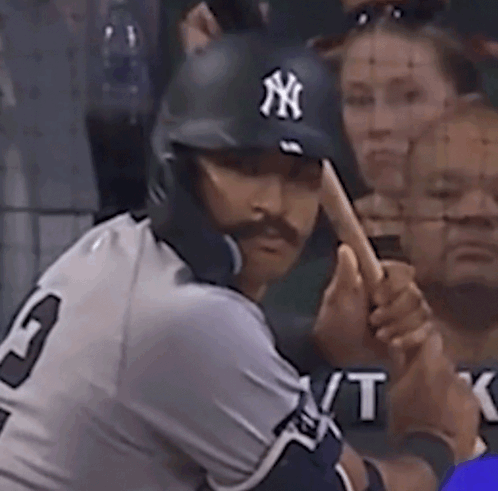 A Man Wearing A Ny Hat Is Swinging His Bat GIF