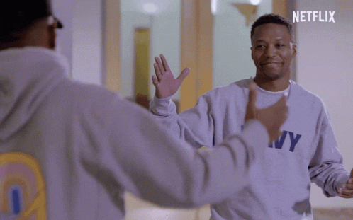 A Man Wearing A Ny Sweatshirt High Fives Another Person GIF