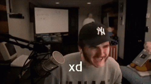 a man wearing a ny yankees hat is smiling in front of a microphone ..