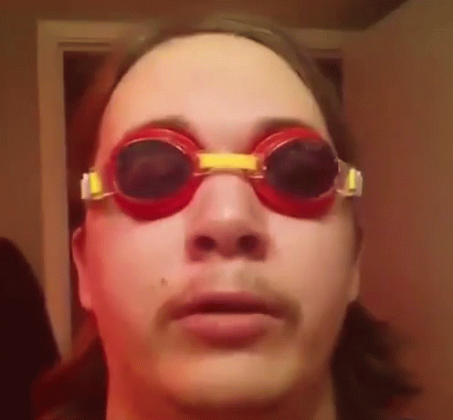 A Man Wearing A Pair Of Red Goggles Looks At The Camera . GIF
