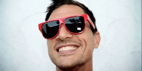 A Man Wearing A Pair Of Red Sunglasses Smiles For The Camera GIF
