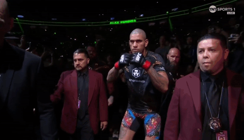 A Man Wearing A Pair Of Ufc Boxing Gloves Stands In A Crowd GIF