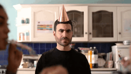 A Man Wearing A Party Hat Is Looking At The Camera GIF
