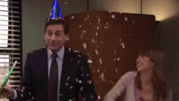 A Man Wearing A Party Hat Is Standing Next To A Woman Who Is Throwing Confetti At Him . GIF