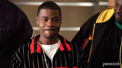 A Man Wearing A Peacock Jacket Is Standing In A Crowd Of People GIF