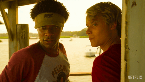 A Man Wearing A Pelican Shirt Stands Next To Another Man In A Red Shirt GIF