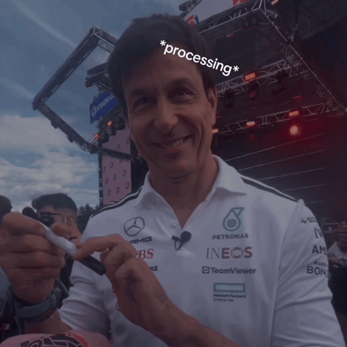 A Man Wearing A Petronas Shirt Holds A Pen In His Hand GIF