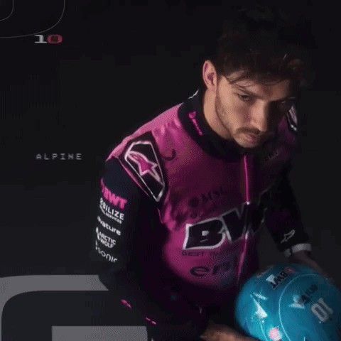 a man wearing a pink and black shirt that says bwt holds a blue helmet