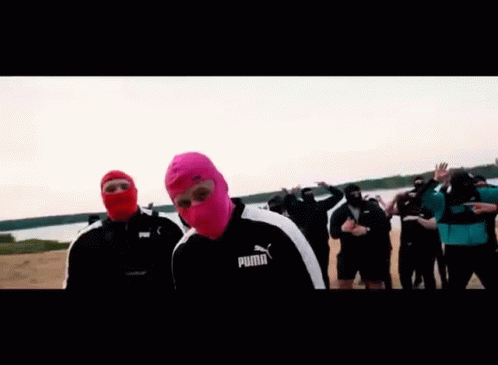 A Man Wearing A Pink Balaclava Is Standing In Front Of A Group Of People . GIF